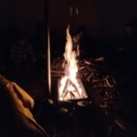 Lagerfeuer in einer Jurte, um das herum Pfadfinder*innen sitzen.