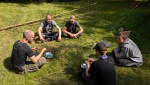 Gruppe mit fünf Leuten sitzt mit Feuerschalen auf dem Boden
