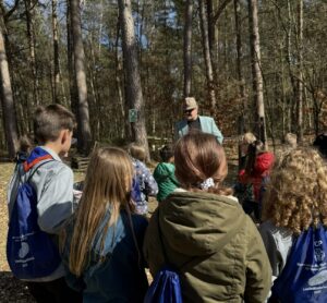 Eine Kindergruppe löst mit Detektiv Pablo Estrado Rätsel im Wald