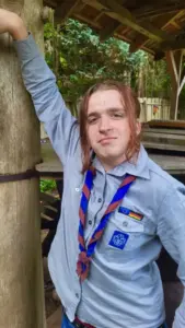 Unser neuer FSJler lehnt sich lässig an den Balken einer Veranda.