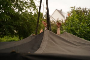 Hände ragen beim Hochziehen einer Jurte aus der Mitte des Dachs.